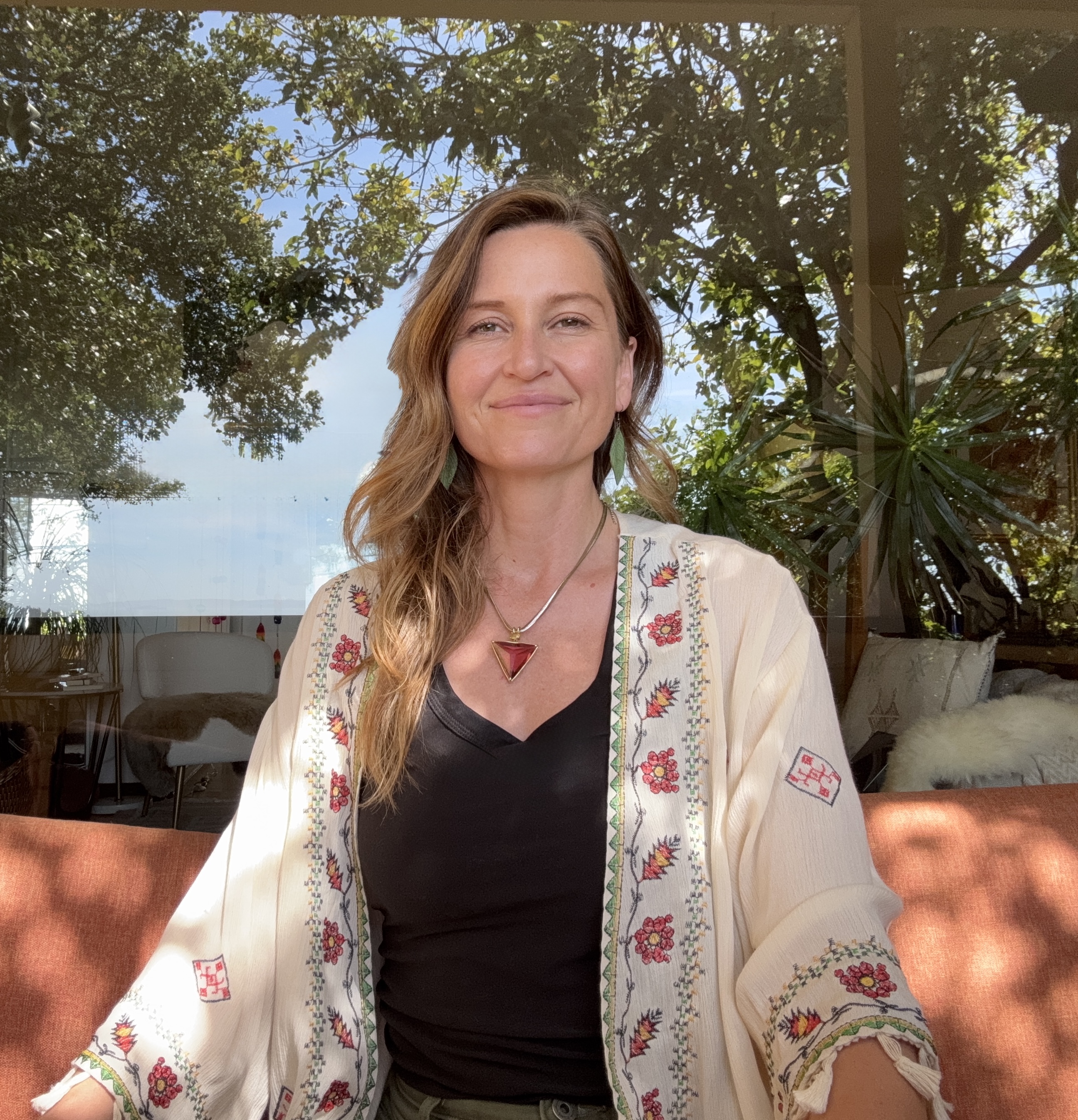 Jen Poole, LMFT, smiling in an embroidered cream jacket beside a sunlit window